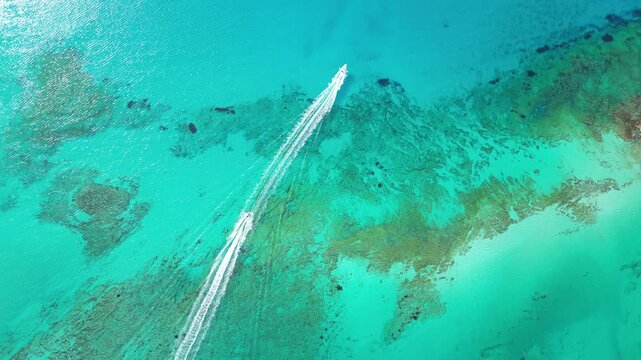 Horizontal top-down drone video of two jet skis crossing Balos Lagoon. White foamy trails cut through vibrant turquoise and azure waters in this stunning aerial view. High quality 4k footage