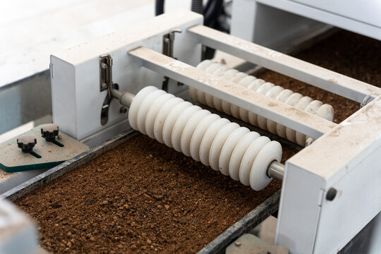 Industrial equipment with roller conveyor transporting coffee grounds material