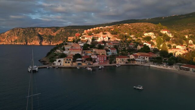 A coastal village with colorful houses cascades down a hillside towards a harbor dotted with boats.