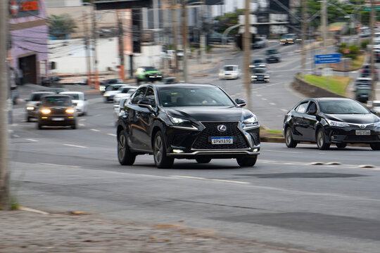 Black Lexus NX front view cruising city street, Luxury SUV driving through urban traffic