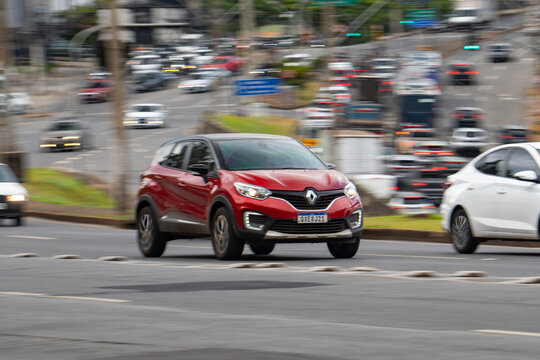 Red Renault Captur front view in movement, Compact SUV driving fast on city avenue