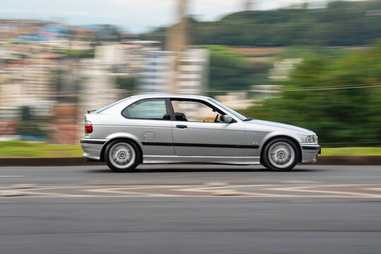 Silver Classic BMW 3 Series side view in movement, Retro sports car cruising city street