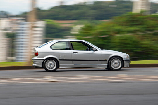 Silver Classic BMW 3 Series side view in movement, Retro sports car cruising city street