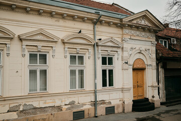 Fototapeta premium Historic residential building facade with decorative elements and wooden door in Zrenjanin, Serbia. European architecture and heritage concept.