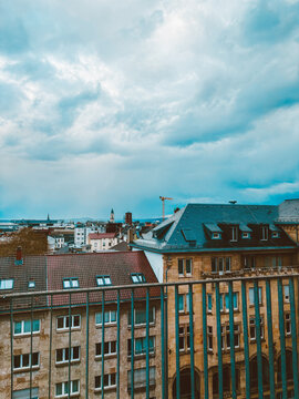 Moody European Cityscape with Historic Rooftops, Church Towers  under Dramatic Cloudy Sky