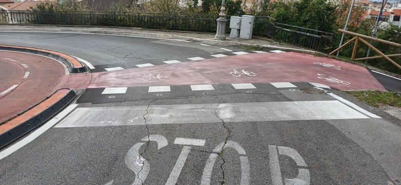 Roter Fahrradweg &Uuml;berweg mit Stopp-Markierung und Fahrrad-Symbolen auf einer italienischen Stra&szlig;e