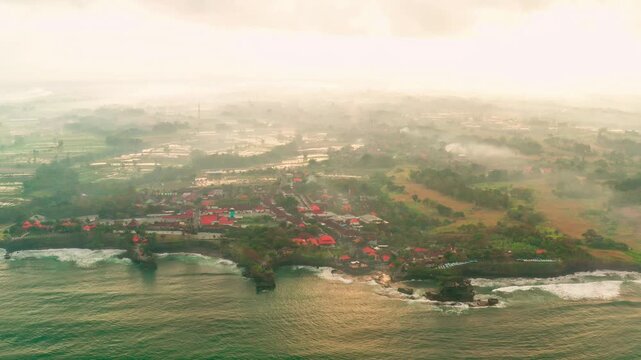 Breathtaking aerial view of of Tanah Lot Temple. Tanah Lot is a rock formation off the Indonesian island of Bali. It's home to the pilgrimage temple Pura Tanah Lot, a popular tourist and cultural icon