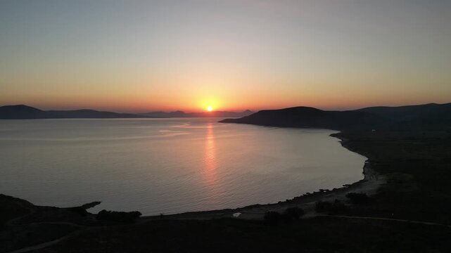 Aerial sunset view over Paralia Skidi beach on Limnos Island, Greece. Golden Mediterranean light reflects across calm sea and quiet shoreline, capturing peaceful natural scenery and evening atmosphere