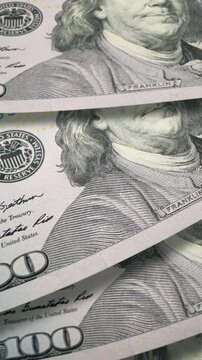 A close-up view of United States one hundred dollar bills stacked with a portrait of a founding father.
