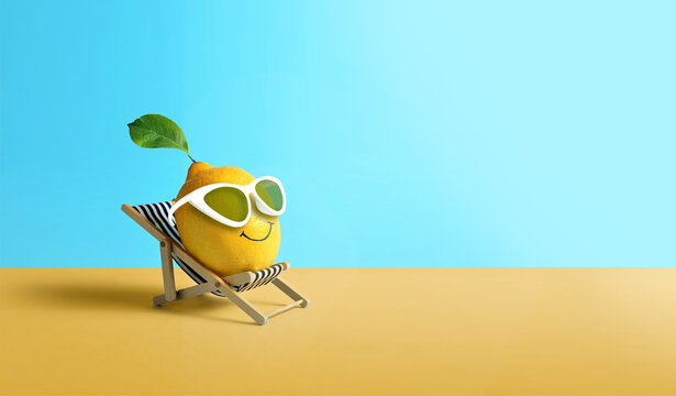 Lemon in sunglasses relaxes on lounge chair on beach. Summer tropical minimal humor concept.