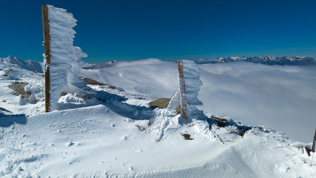 Frozen wooden fence posts with rima ice on a snowy mountain peak.