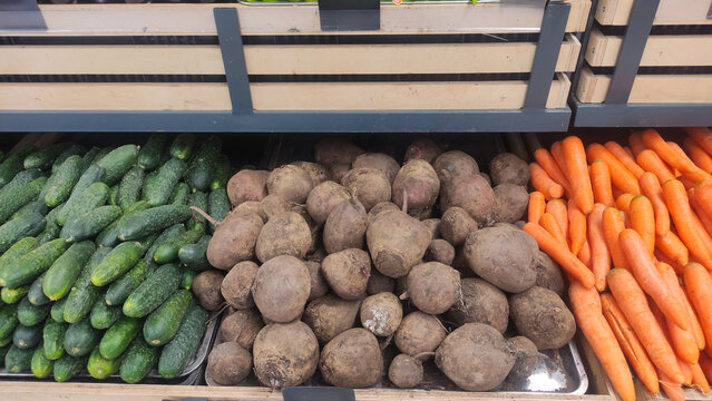 Assortment of fresh vegetables including cucumbers, beets, and carrots neatly arranged in a grocery store display, highlighting natural produce and healthy eating choices.