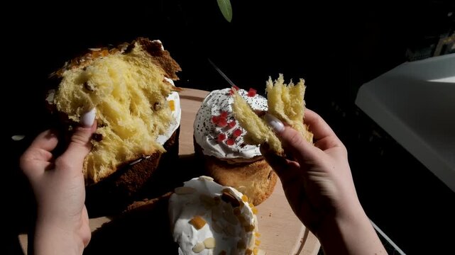 Soft Easter breads tasting moment as female hands tear and eat fluffy paska kulich and colomba enjoying fresh sweet crumb in cozy festive atmosphere