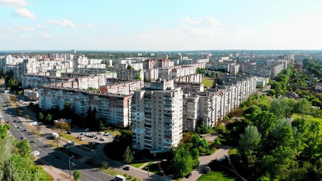 Drone shot of the 10th microdistrict in Sumy, Ukraine, with densely built-up residential buildings in a typical residential area. Busy road with moving traffic, green urban areas.