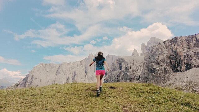 Tracking follow pov excited female fit hiker runs enjoy sunny iconic famous Italy Dolomites mountains range. Mountain trail breathtaking views iconic limestone peaks. UNESCO World Heritage site