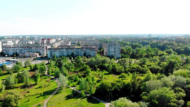 Drone shot of the 10th microdistrict in Sumy, Ukraine, with densely built-up residential buildings in a typical residential area. Busy road with moving traffic, green urban areas. 
