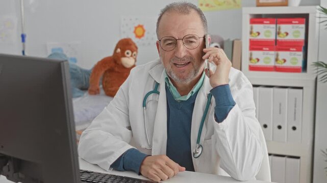 Man doctor holding smartphone to ear speaking on phone with stethoscope and computer visible in building; concerned telemedicine support.