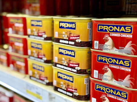 Depok, Indonesia - March 31, 2026: A variety of Pronas brand canned corned beef and chicken products neatly arranged on a retail aisle rack at Tip Top Supermarket in Depok. 