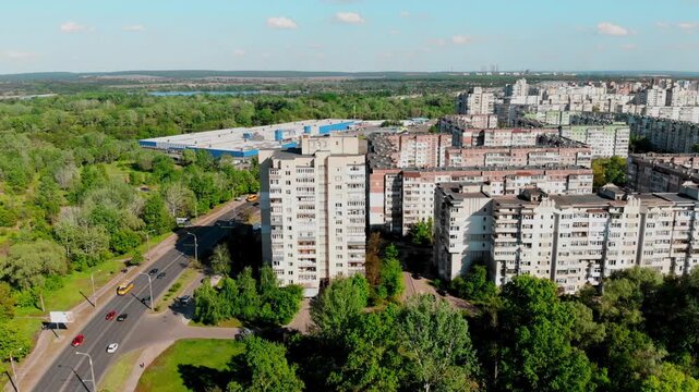 Drone shot of the 10th microdistrict in Sumy, Ukraine, with densely built-up residential buildings in a typical residential area. A busy road with moving traffic, green urban areas 