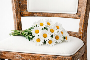 Close-up of a bouquet of white daisies on an old chair © Mimi B