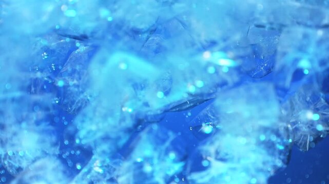 Ice cubes falling into water with oxygen bubbles, frost patterns, and soft light reflections. Concepts for beauty advertising, menu designs for bars and restaurants, cryotherapy.