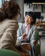 Business women collaborating on mobile phone in office