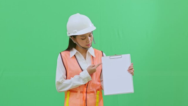 A female supervisor pointing at a specific data point on her clipboard. Highlighting safety issues or technical details during a site review on green screen.