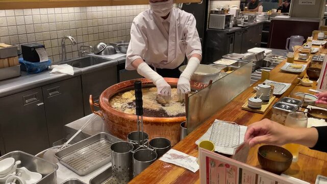 Osaka, Japan - March 27, 2026: Chef Frying Tempura in Traditional Copper Pot at Japanese Restaurant Counter