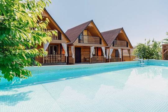 Wooden cottages with swimming pool, sunny summer vacation resort with clear blue water, homestay