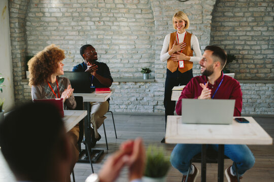 Team applauding female speaker at business conference or startup meetup