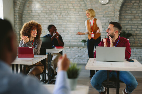Group of diverse business people applauding a smiling woman standing at a seminar