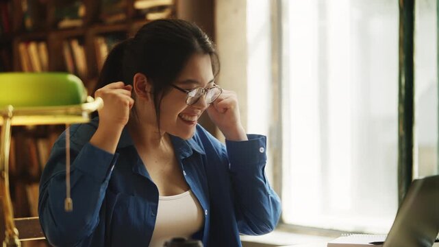 Cheerful Asian woman student celebrating good news email, passed the test