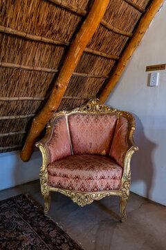Vintage Ornate Armchair Beneath Rustic Thatch Roof Interior