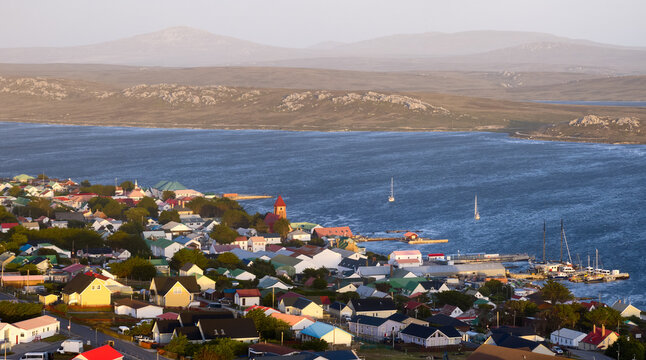 Aerial view of Stanley harbor and colorful townscape with calm bay and soft natural light, Falkland Islands. Clear coastal composition, ideal for: travel promotion, destination marketing, copy space.