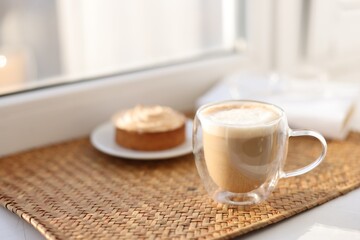 Obraz premium Aromatic coffee in glass cup and delicious tart on windowsill, closeup. Space for text