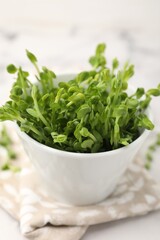 Fototapeta premium Fresh microgreens in bowl on white table, closeup