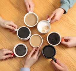 Friends with cups of aromatic coffee at wooden table, top view