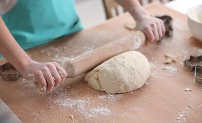 Obraz premium Child rolling dough at wooden table indoors, closeup