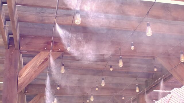 Water spray system for cooling the terrace on a hot summer day. Fogging system, high pressure water spray. Wooden ceiling in loft style.