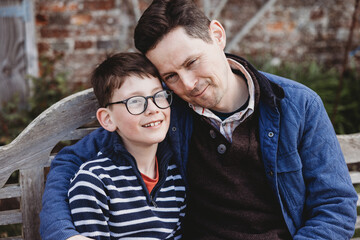 Fototapeta premium Father and son sitting together outdoors sharing warm family moment on bench
