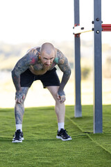 Obraz premium Tattooed man resting during outdoor fitness workout