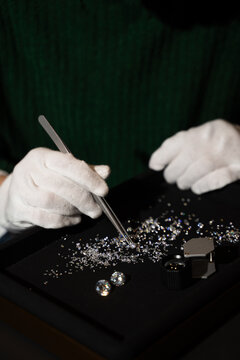 Gemologist holds a small diamond with tweezers for precise inspection and sorting.