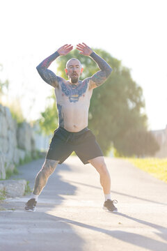 Tattooed man exercising outdoors performing a fitness workout