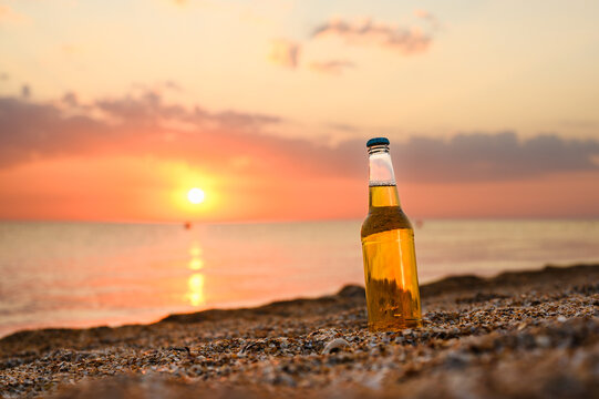 A bottle on the seashore. Beer against the sunset. Summer vacation by the sea.