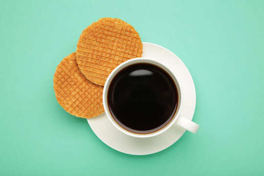 Traditional local authentic Dutch Netherlands sweet fresh homemade tasty stack brown golden waffle melt salted caramel with hot warm coffee. Stroopwafel on mint background