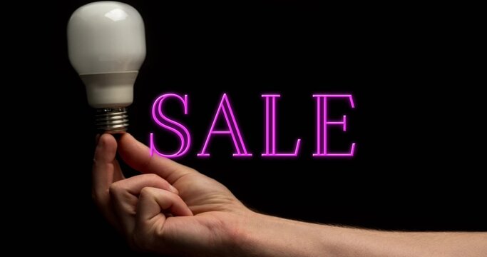 Extending forearm and hand from right edge in studio, holding LED bulb, magenta SALE neon glowing