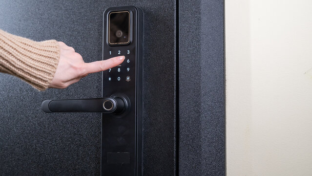 A woman opens a modern smart door lock with a digital keypad using a code.