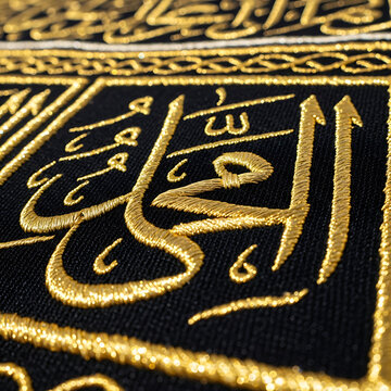 Close up of islamic calligraphy with gold embellishments on black fabric