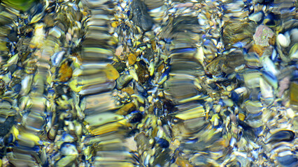 Fototapeta premium An artistic photograph capturing the distortion, reflection and refraction of light in moving water against a colourful background.