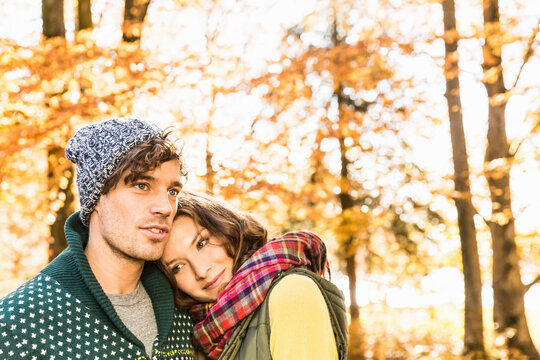 Couple Standing in an Autumn Forest with Her Head Resting on His Shoulder.